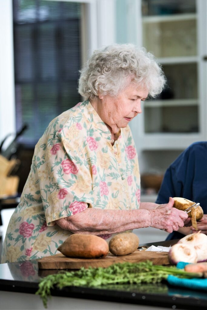 Elderly woman learning to peel potatoes after a stroke